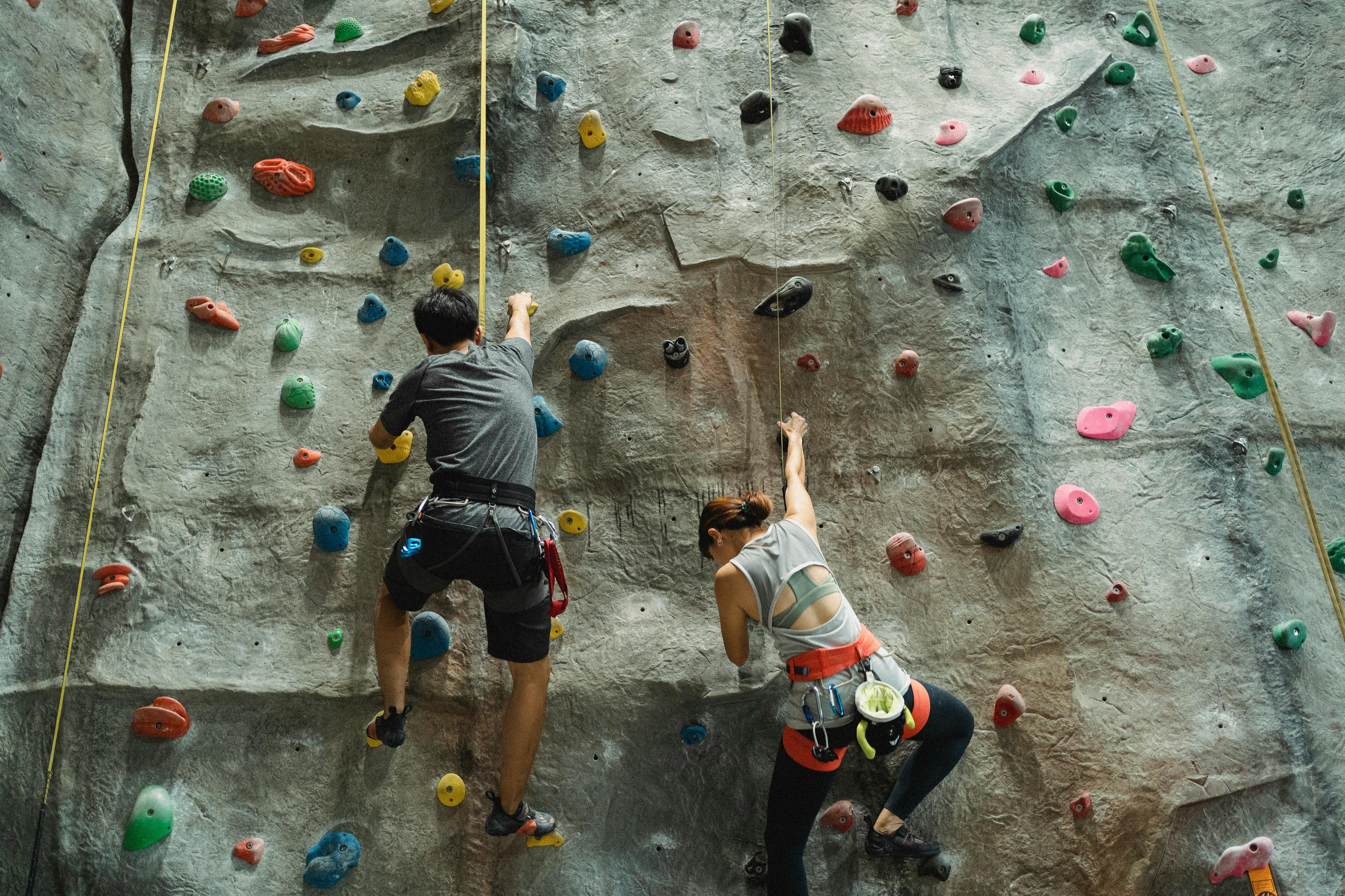 unrecognizable athletes practicing climbing in bouldering gym