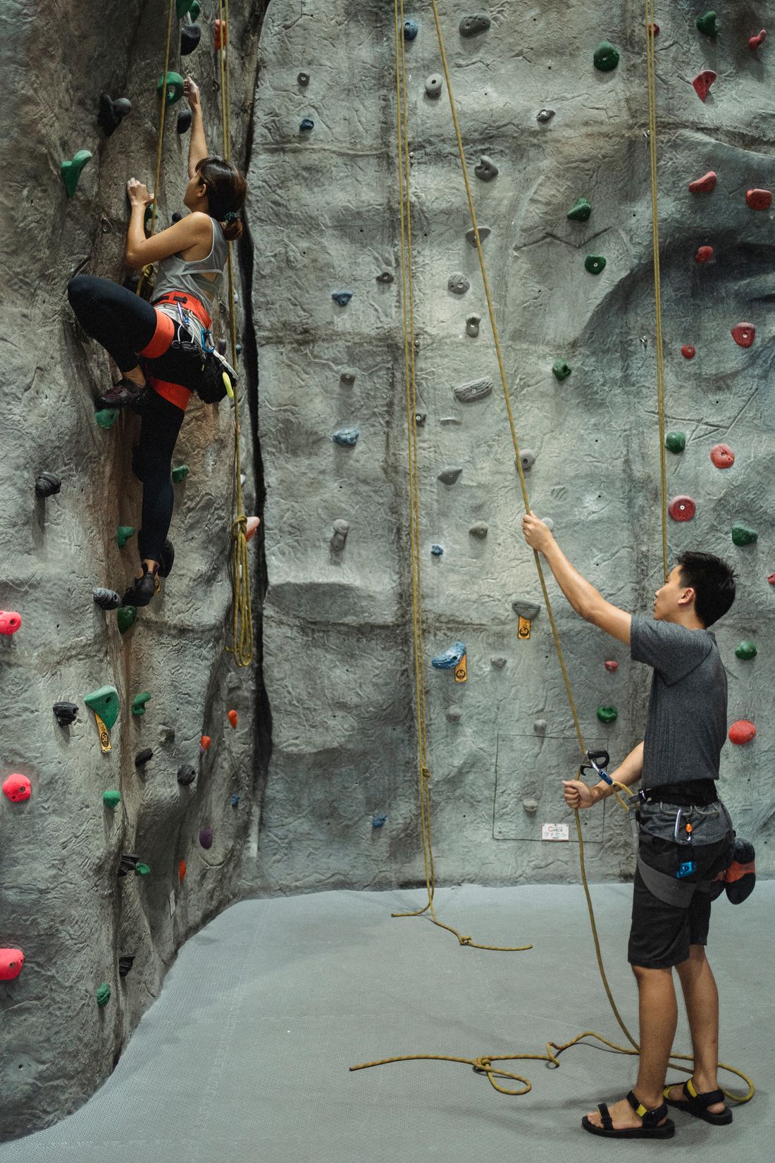 An instructor belaying a climber on the top rope walls