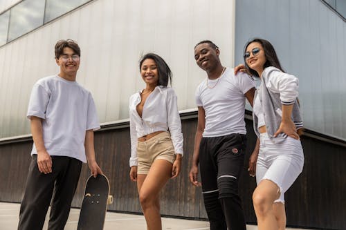 Happy diverse millennials relaxing on street after skateboarding