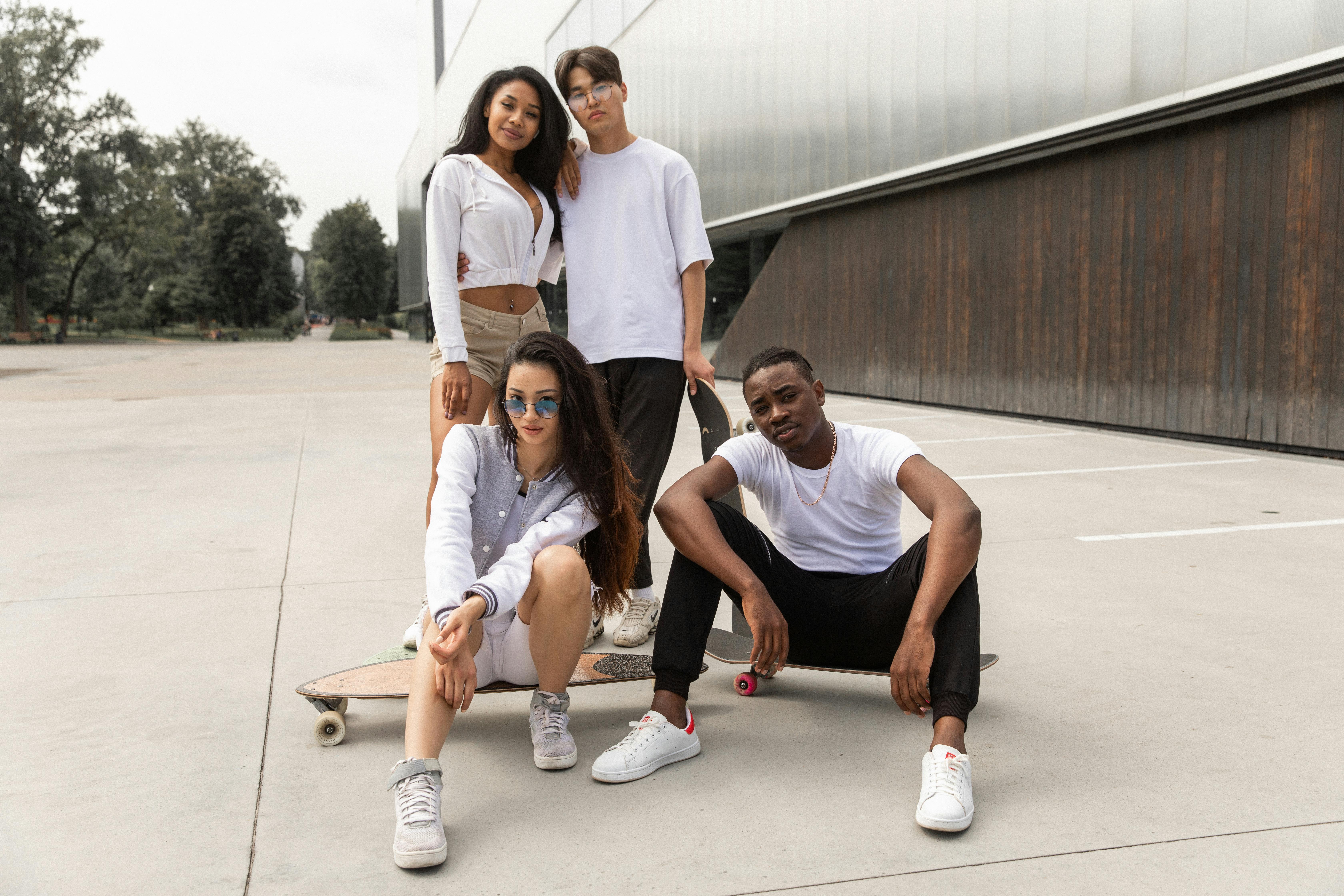 confident diverse young sporty millennials standing in city park with skateboards after workout