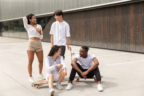 Content young diverse sportspeople communicating after skateboarding together in park