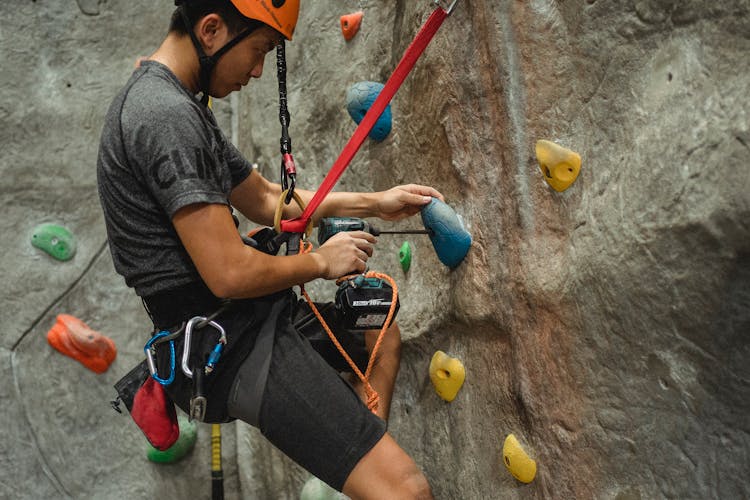 Crop Asian Climber Fixing Hold On Artificial Rock