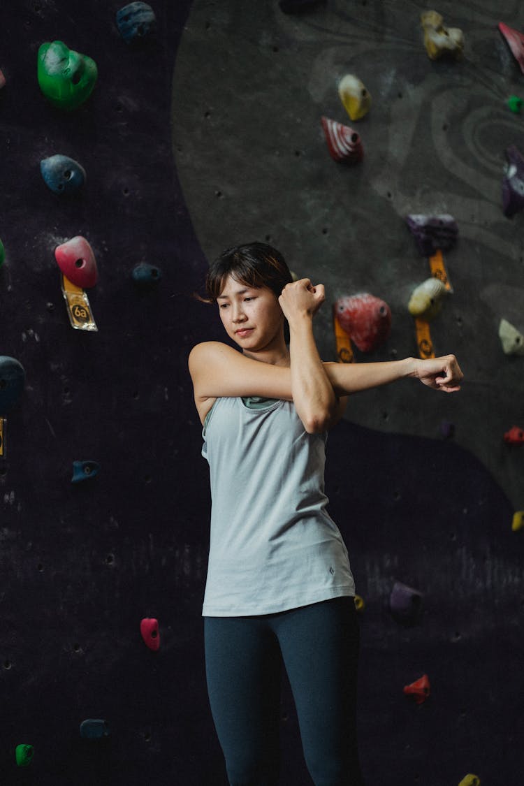 Asian Climber Warming Up While Training Near Climbing Wall