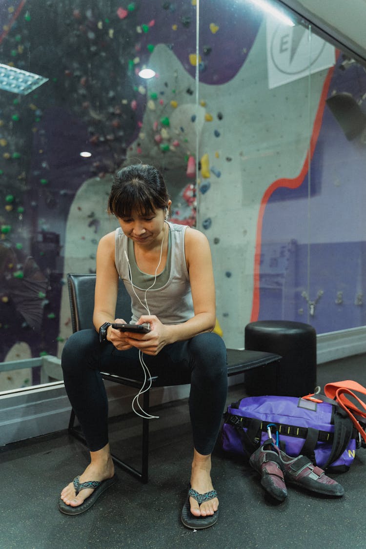 Asian Climber Chatting On Smartphone Near Artificial Rock