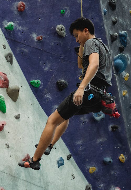 Free Asian male climber ascending artificial rock during training Stock Photo
