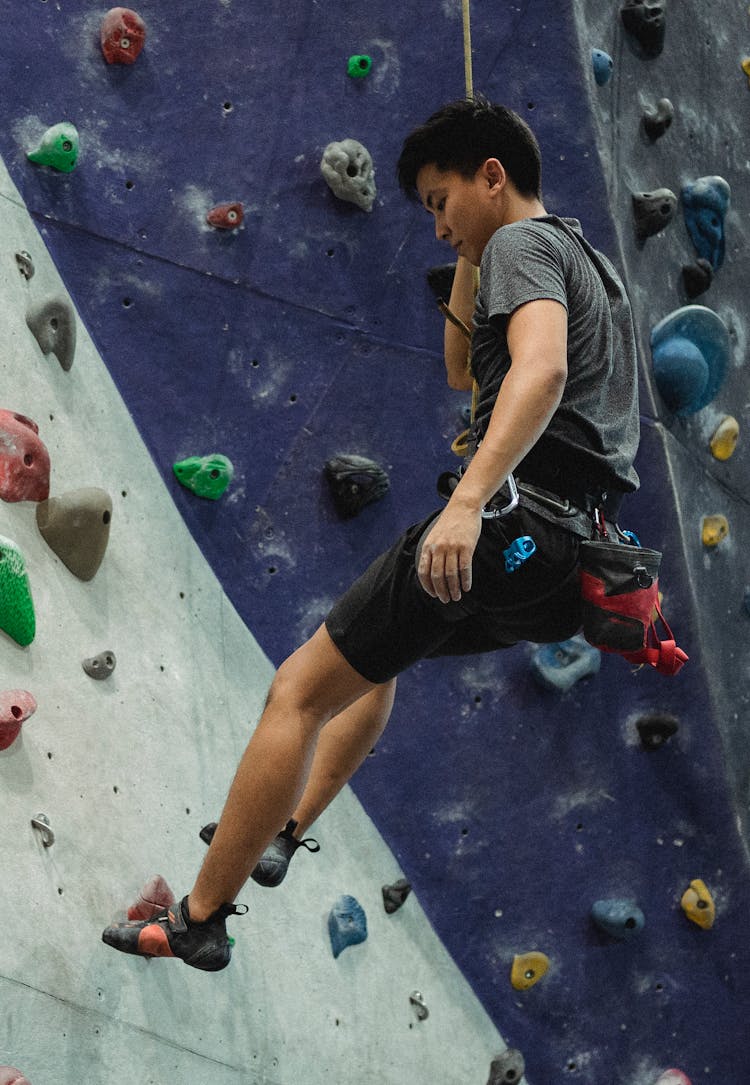 Asian Male Climber Ascending Artificial Rock During Training