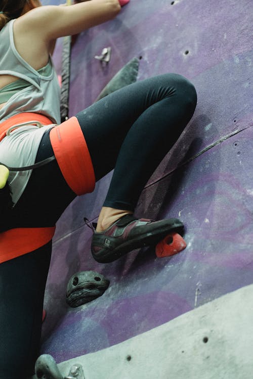 Crop mountaineer climbing wall with holds during training