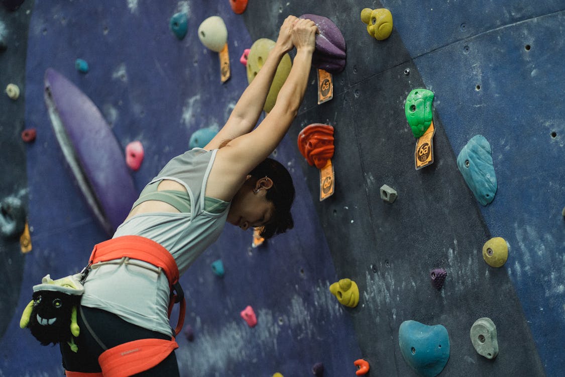 Sportswoman stretching before training in climbing center · Free Stock Photo