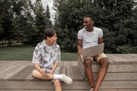 Cheerful young multiracial male friends browsing laptop in park
