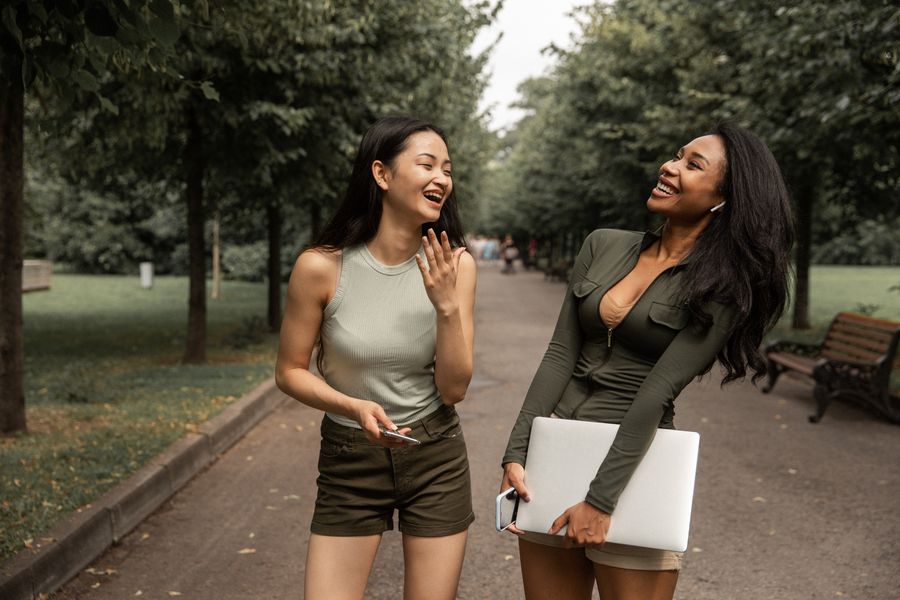 Two friends laughing together in a green park