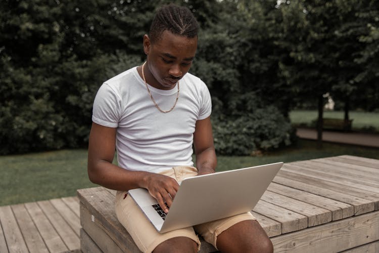 Concentrated Young Self Employed Ethnic Guy Working On Netbook In Park