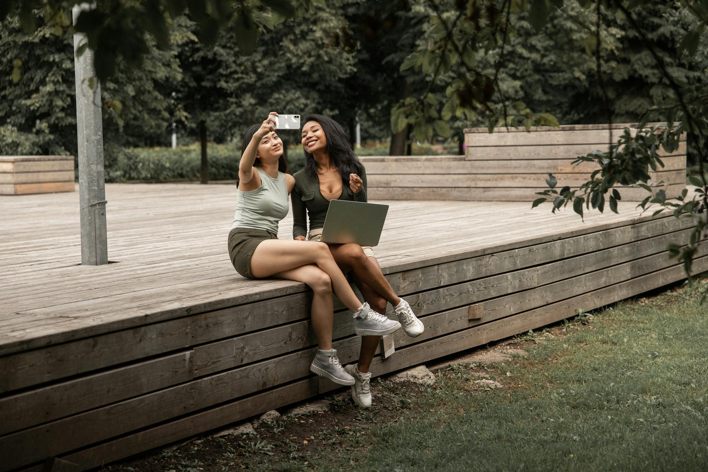 Cheerful women taking selfie in park 