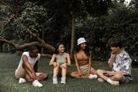 Group of multiracial friends relaxing on grass in park while speaking and looking at each other