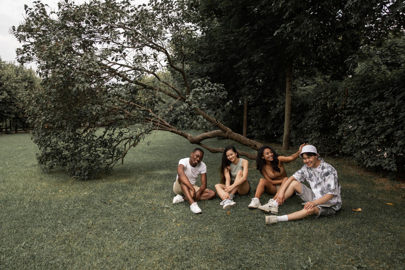 Diverse group of friends sitting together and smiling in a park