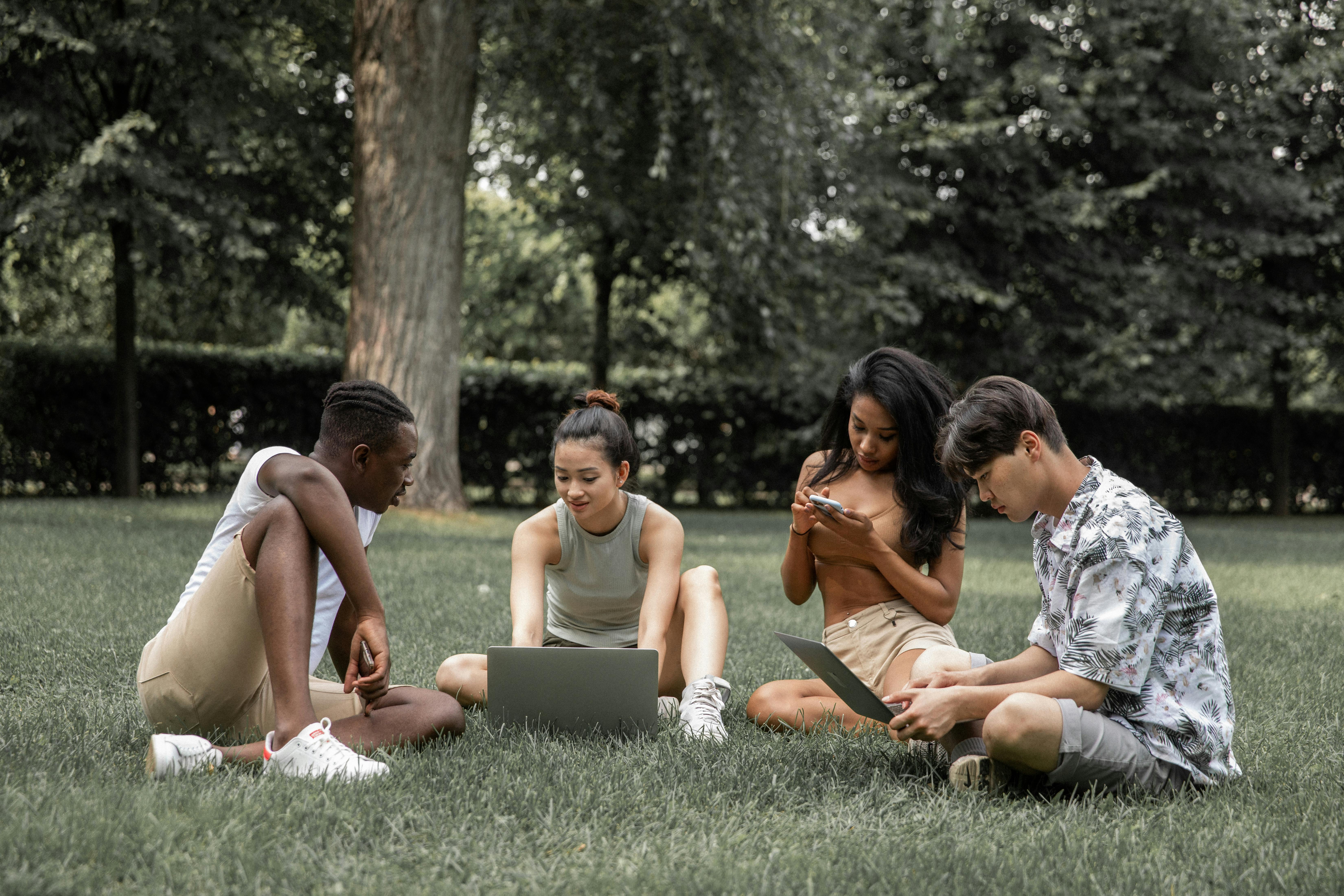 diverse students with gadgets in park