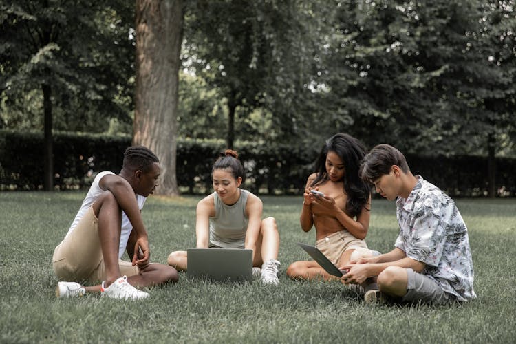 Diverse Students With Gadgets In Park