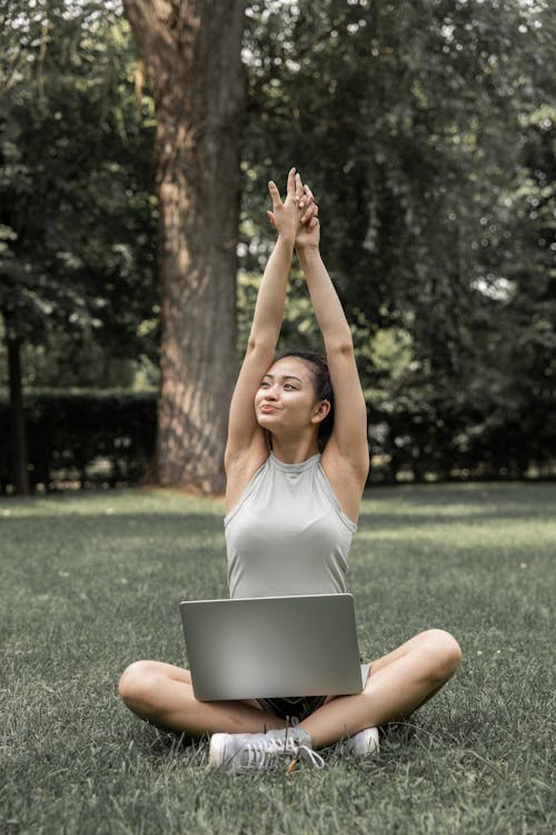 Cheerful woman stretching arms during online studies