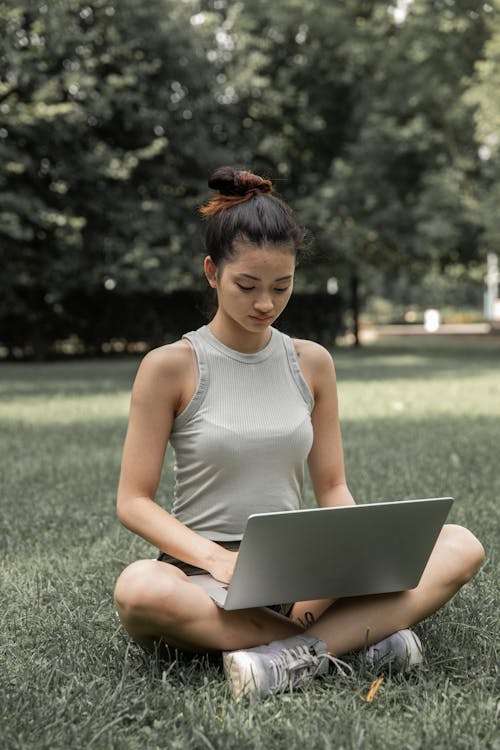 Asian woman browsing laptop in park