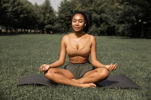 Free Fit ethnic woman practicing yoga in park Stock Photo