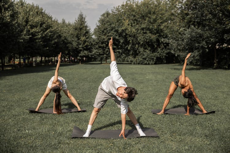 Multiethnic People Practicing Yoga In Park