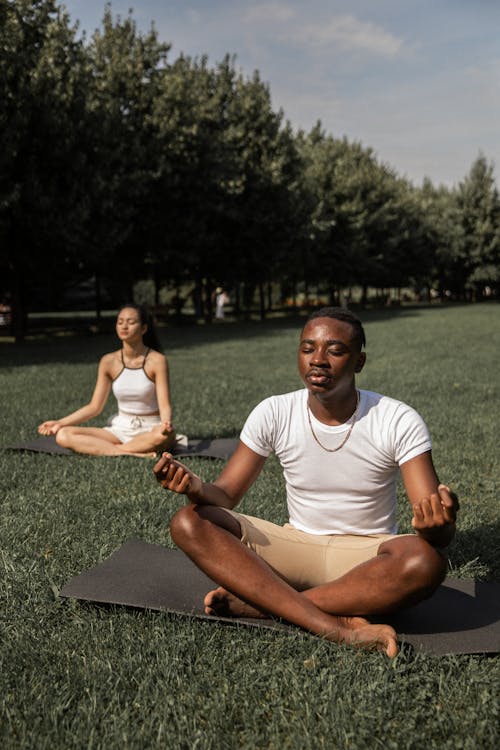 Free Full body of flexible barefoot couple in activewear sitting on mats in Lotus pose with closed eyes while practicing yoga together Stock Photo