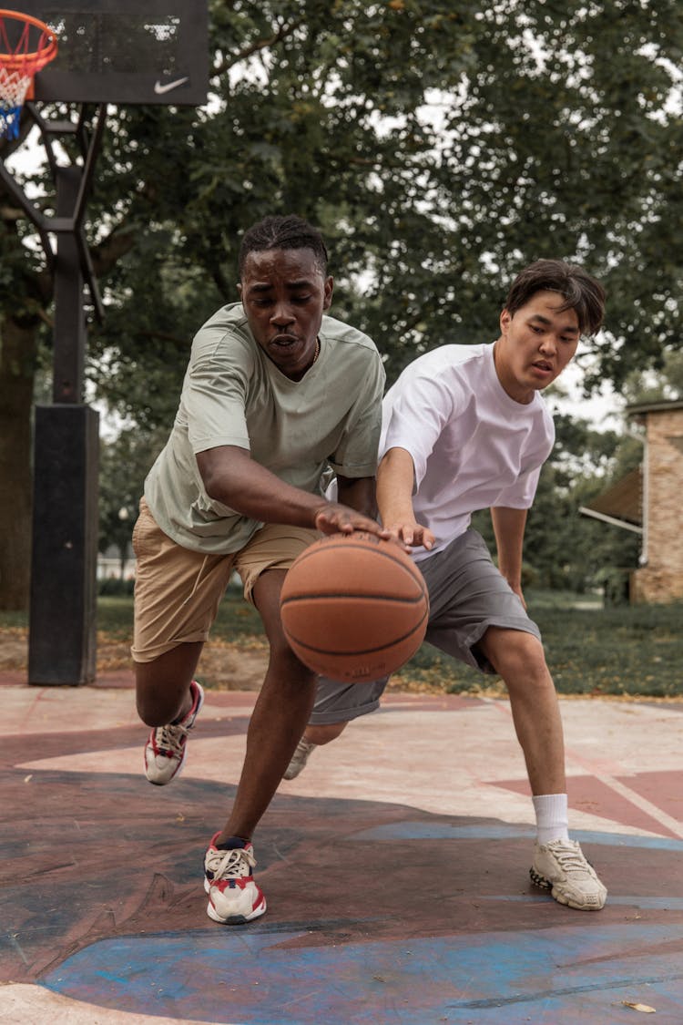 Concentrated Men Playing Basketball On Court