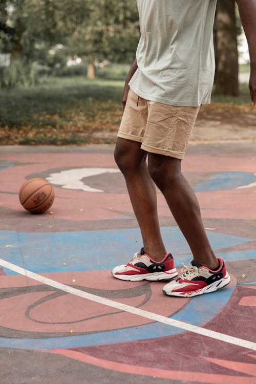 Crop faceless black man playing basketball on sports ground