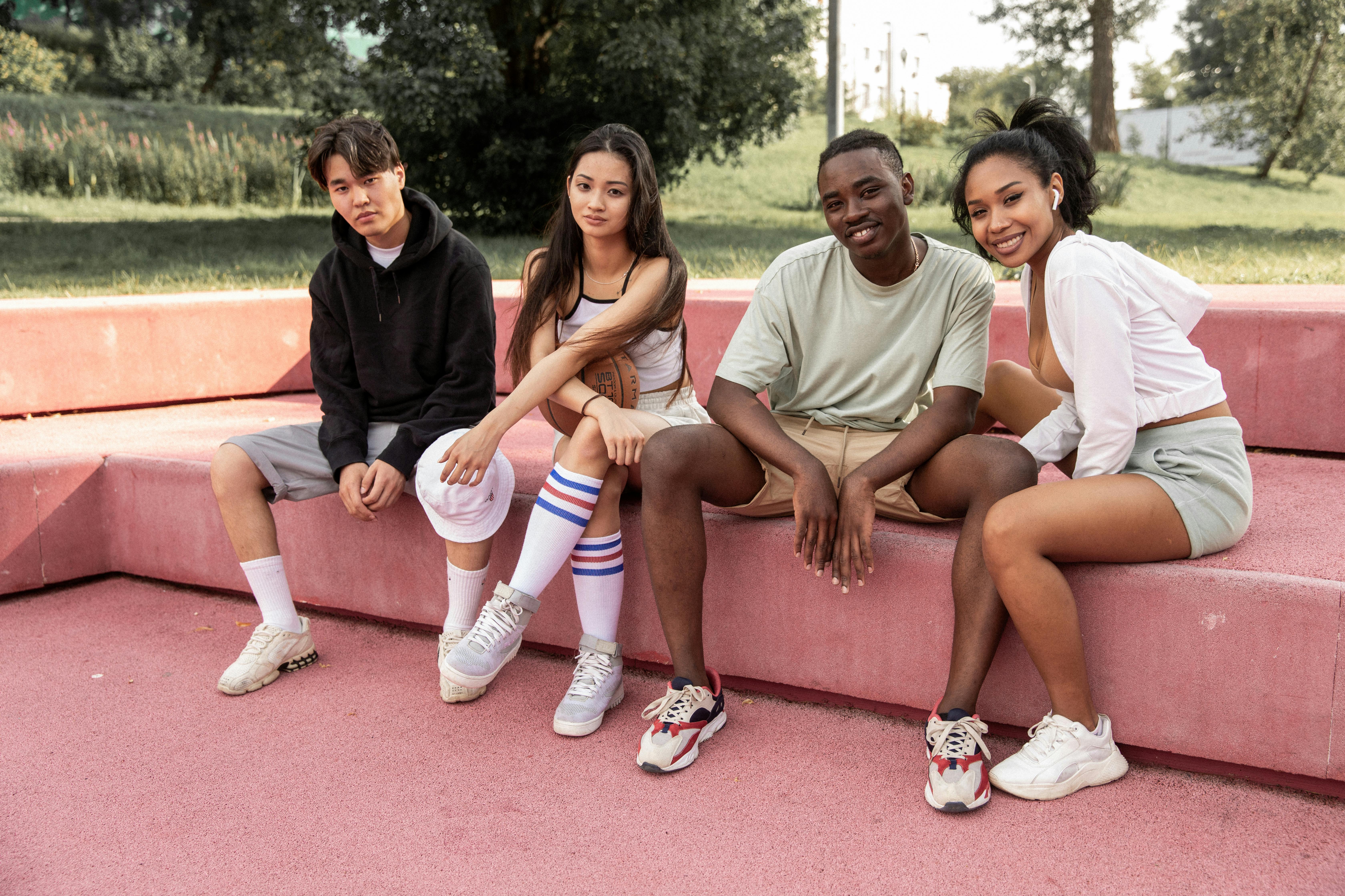 happy diverse friends resting on stone bench in park