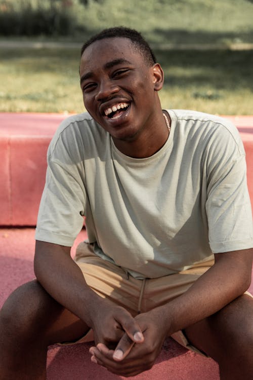 Free Laughing black man sitting on bench in park Stock Photo