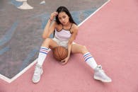 自信的年轻女子穿着休闲运动服，在户外球场上拿着篮球摆姿势