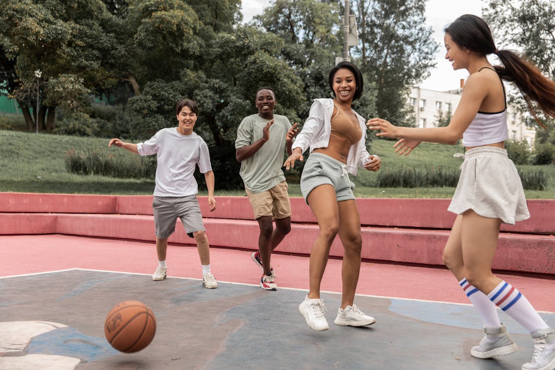 Free Delighted multiethnic friends playing basketball in park Stock Photo