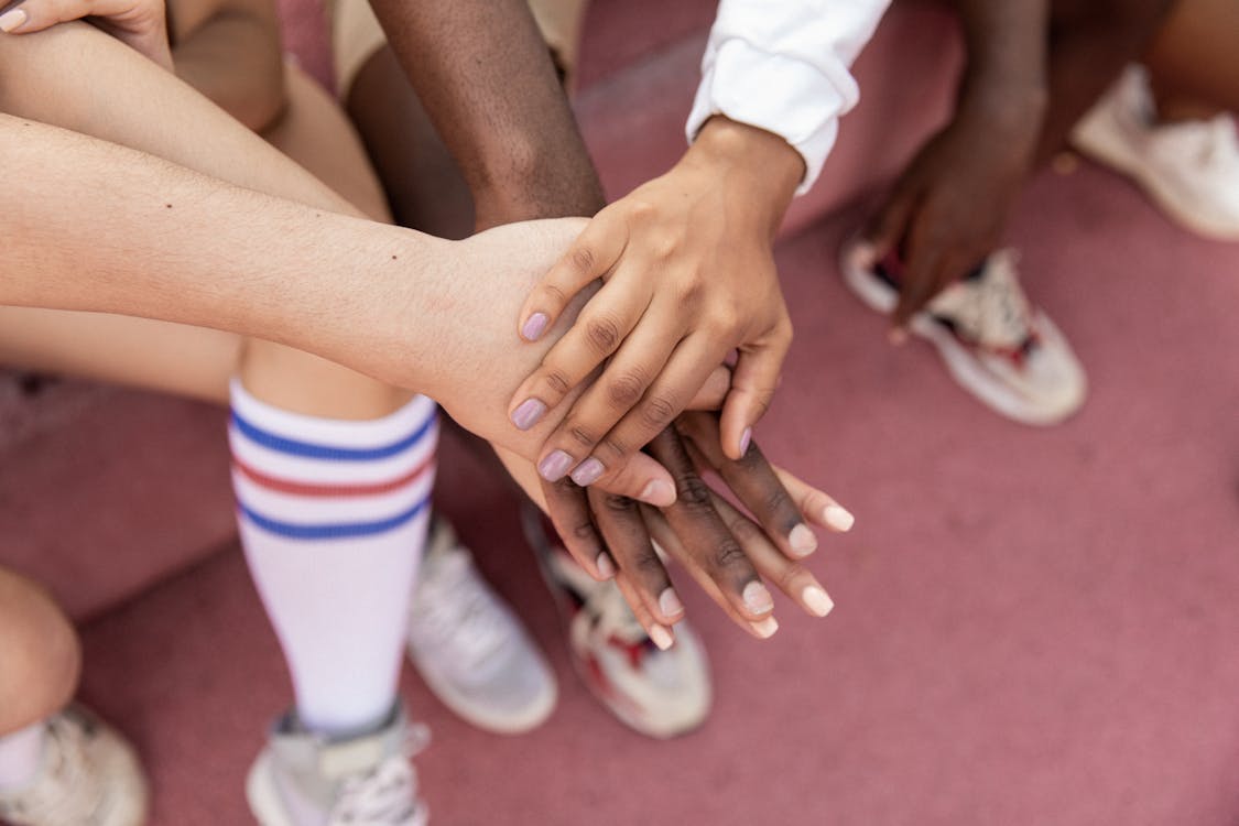 Free Faceless multiracial sport team stacking hands on court Stock Photo