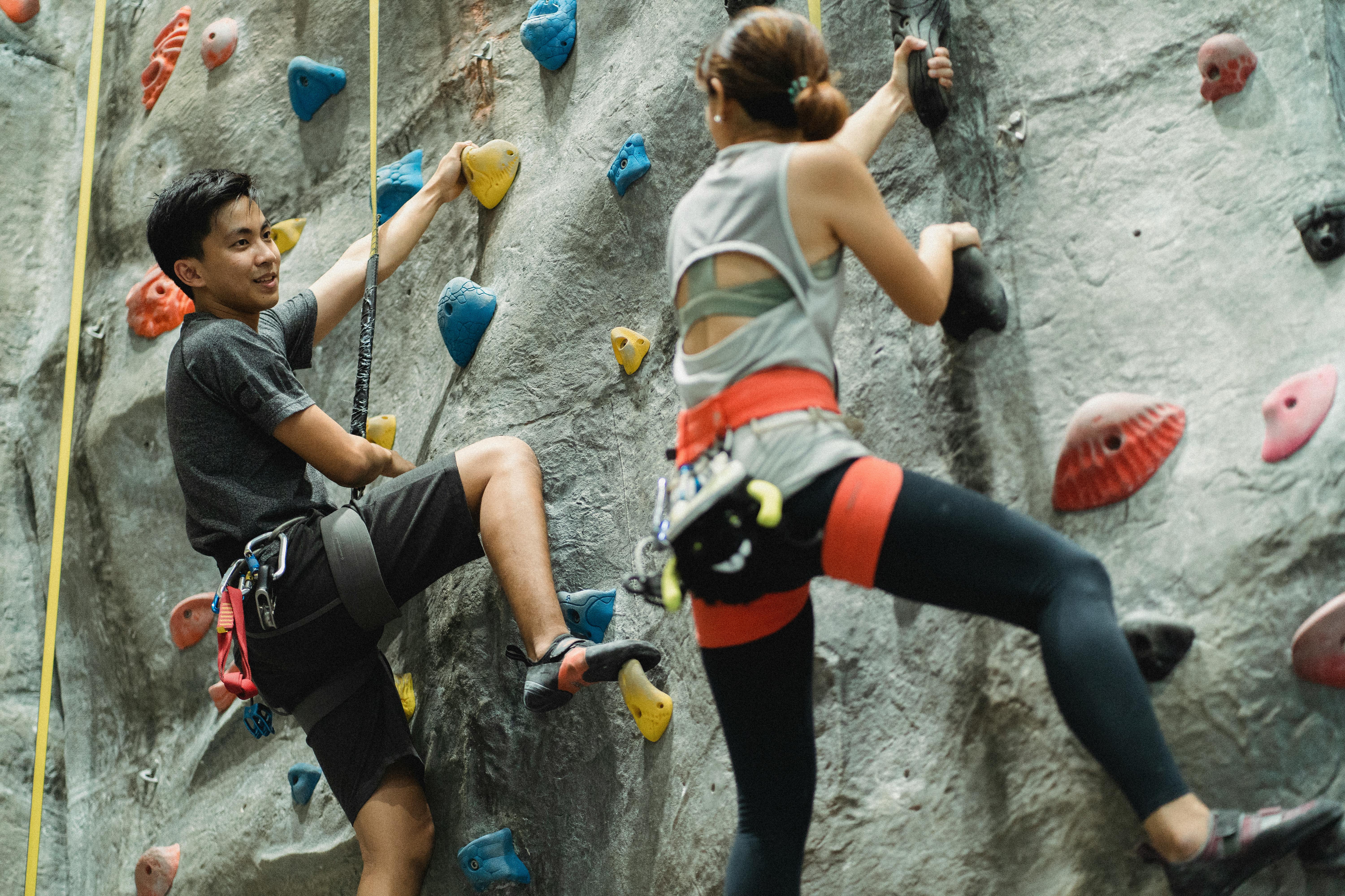 sportspeople training on climbing wall in gym