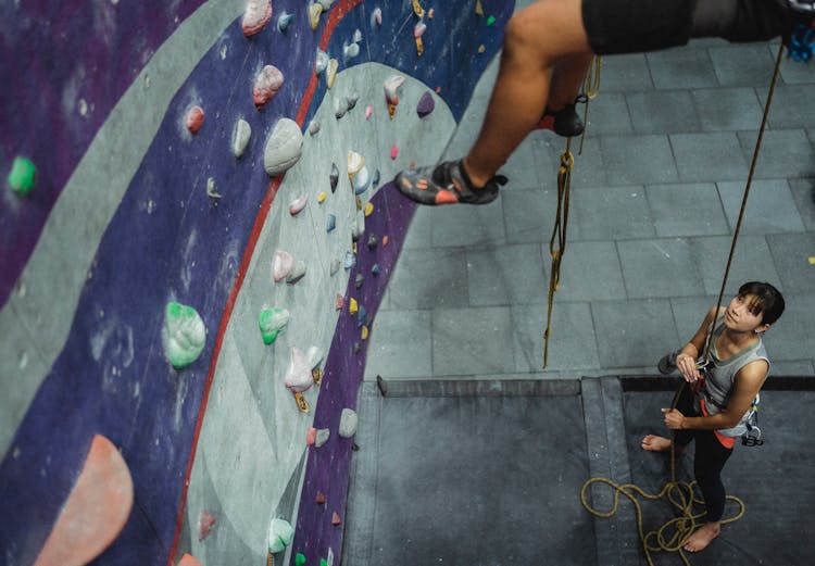 Focused Woman Helping Climber With Belay