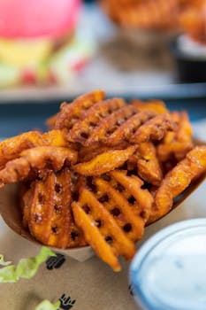 Delicious crispy waffle fries served with dip sauce in a Vienna café, perfect for food photography.