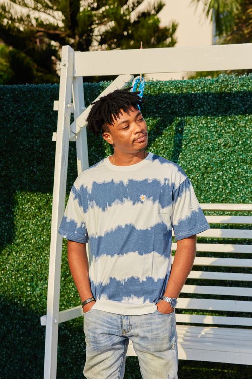 Free Casual outdoor portrait of a young man in tie-dye t-shirt and jeans, enjoying the sun. Stock Photo