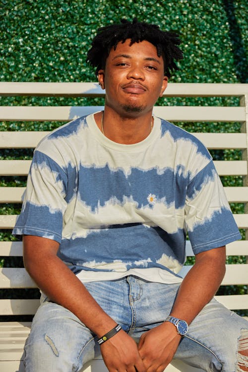 Man in Blue and White Crew Neck T-shirt Sitting on White Wooden Bench