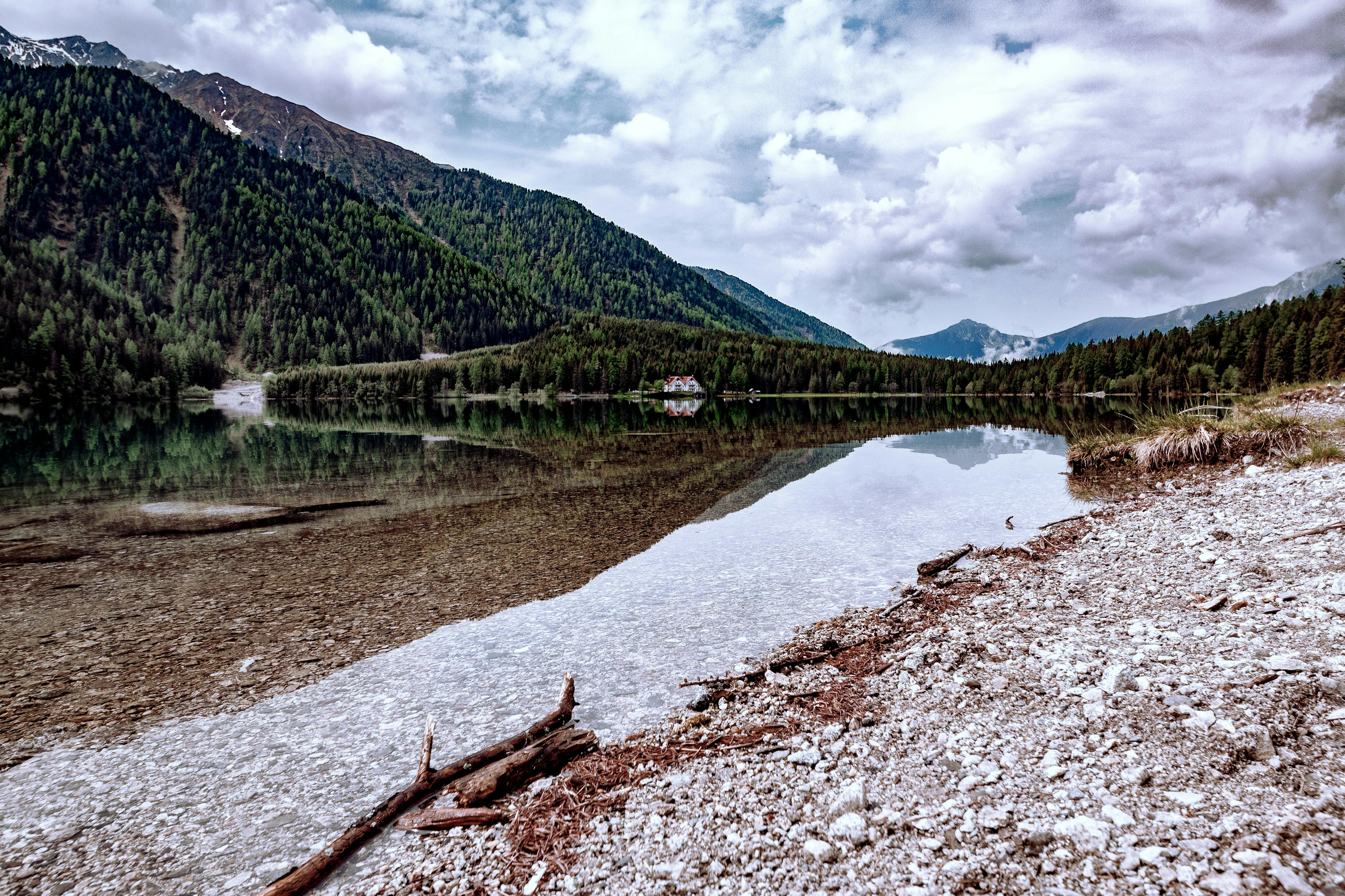 Tranquil lake with mountain reflections and cloudy sky, showcasing natural beauty.