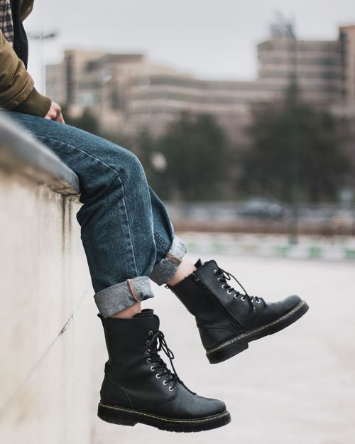 Free Person sitting on a concrete wall in black boots and denim jeans Stock Photo