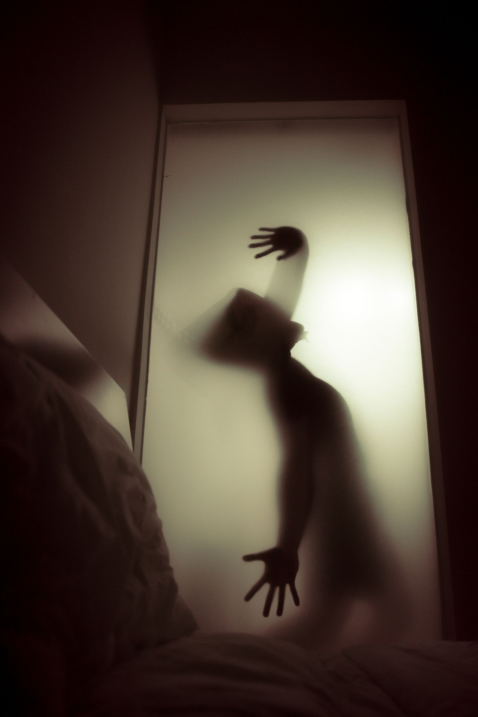 A silhouette visible through frosted glass, its shape clear but its hands unreadable
