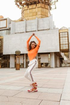 一位穿着鲜艳服装的女人在现代建筑前充满活力地跳舞