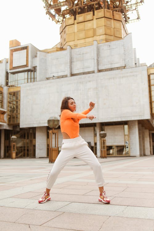 Woman Dancing Wearing Orange Long Sleeves and White Pants 