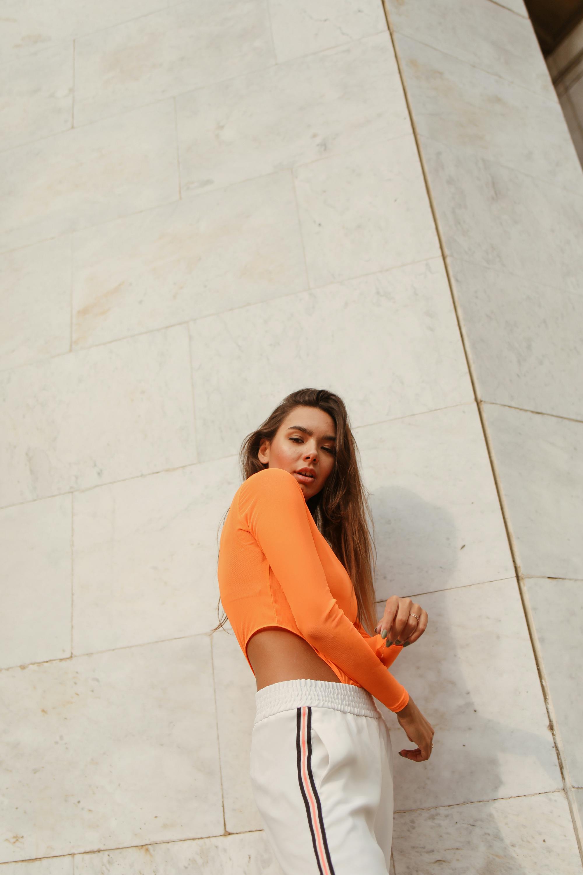 low angle shot of woman posing near the white marble wall