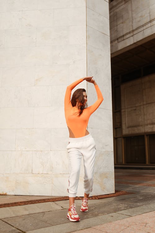 Free Woman in Orange Long Sleeve Shirt and White Pants Dancing Stock Photo