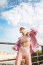 一位穿着时髦运动装、充满自信的女人站在晴朗的户外天空下