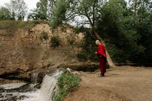 A Bald Man Standing Near the Waterfall 