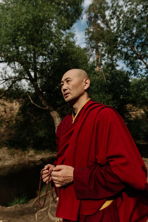 Free A Buddhist monk meditates with prayer beads in a peaceful natural setting. Stock Photo