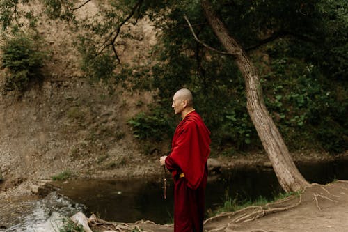 Man Standing Near the Body of Water Holding a Prayer Beads 