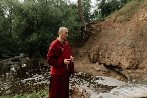 Man in Red Robe Standing Near the Waterfall
