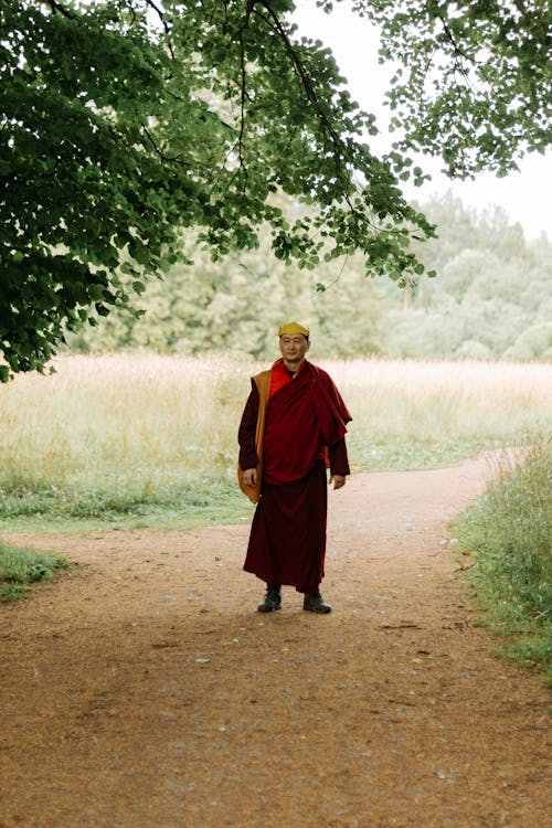 Man in Red Monk Shawl Standing Under the Tree 